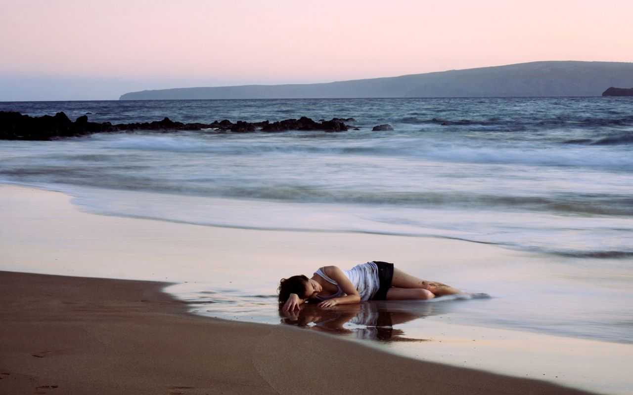 Почему любят море. Девушка лежит на песке у моря. Человек лежит на песке. Море одиночество. Одинокая на берегу моря.