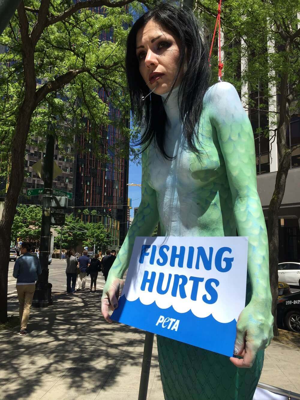 ‘Sirena’ toples enganchada y pendiendo, en protesta de la crueldad de la industria pesquera | Blog | PETA Latino